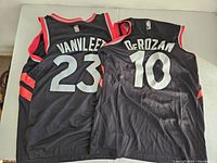 Back view of two black Toronto Raptors jerseys with player's names VanVleet #23 and DeRozan #10.
