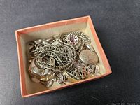 Photo of a collection of mixed sterling silver jewelry and scrap in a small box showing chains, rings, and pendants.