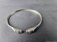 Top view of sterling silver open cuff bracelet showing smooth band and lion head ends.