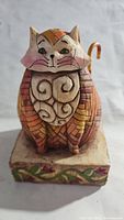 Front view of stylized Elijah Cat figurine showing facial features, chest swirls, and base vine design.