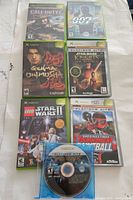 Top view of 7 original Xbox video games laid out on a flat surface showing cover art and disc for one game.