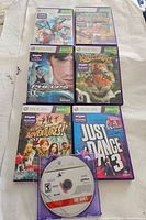 One photo showing six Xbox 360 Kinect game cases arranged on a light surface and one loose disc.