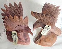 Pair of wooden carved eagles with hand carved tags attached, showing distinct wing feathers and base