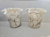 Pair of glass vases seen from front showing cream color, brownish veining, and ruffled edges.