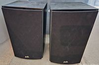 Front view of the pair of Polk bookshelf speakers with black front grilles and Polk branding at the bottom.