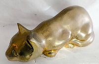 Close-up side view of the brass cat statue showing the smooth contours and brass patina.