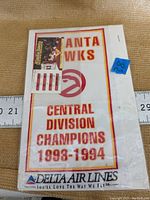 Close-up front view of the rectangular cloth banner with red and yellow border, Atlanta Hawks text, logo and Delta Air Lines branding, displayed with ruler for size reference.
