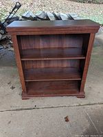 Front view of wooden book case showing two shelves and inline wood grain finish.