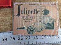 Overall image of the Julinette hair net paper package with ruler for size reference.
