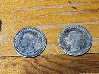 Close-up of the two coins from Great Britain featuring Queen Victoria with visible age wear and tarnishing on the surfaces.