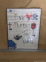 Front view of framed artwork showing the hand drawn replica of Pink Floyd The Wall album cover with white bricks and various illustrations.