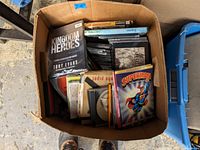 Top view of large box filled with mixed CDs, DVDs, and some books or game cases showing the variety and condition of items included.