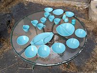 Full set of robin's egg blue Vernonware dishes, cups, serving dishes, salt and pepper shakers, and condiment bottles arranged on glass table outdoors.