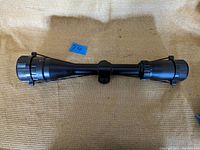 Top view of black spotting scope showing cylindrical body with flared objective lens and eyepiece ends, focusing knob in middle.