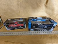 Both diecast model cars in their original boxes, placed side by side with ruler for scale reference.