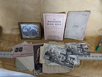 Photo showing the assortment of vintage paper items including booklets, postcards, tickets, and letters arranged on a tabletop.