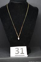 Full view of 18-inch 14K gold chain necklace with marquise-cut clear stone pendant displayed on black bust