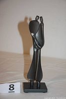 Front view of the black steel sculpture titled Family by Boris Kramer depicting two adult figures holding a child figure.