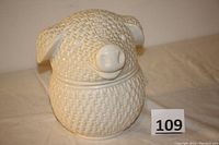White ceramic pig-shaped cookie jar with basket weave pattern, showing full front and side view to highlight shape and texture.