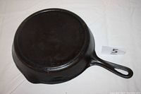 Bottom view of cast iron skillet showing flat base and handle with auction marker.