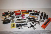 Wide view of all locomotives, cars, track, switches, power packs laid out on white surface.