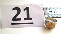 Lot number card “21” and silver ring with ruler for scale