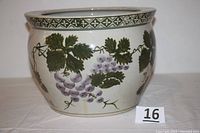 Side view of large porcelain planter showing grapevine artwork and decorative rim pattern.