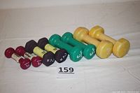 Full lot showing eight dumbbells in descending weight order with two each of 1 lb (red), 2 lb (dark brown), 3 lb (green), and 5 lb (yellow).