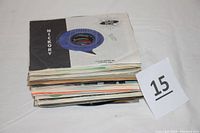 Stack of approximately 41 vintage 45 RPM vinyl records with various paper sleeves, stacked horizontally.