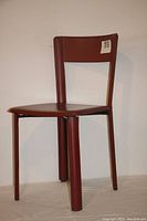 Front view of red faux leather chair showing seat, backrest, and four legs covered in matching material.