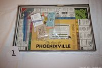 Game board inside a clear box with play money and instruction cards on top.