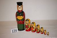 Photo showing full set of 7 handpainted nesting dolls or jars arranged in descending order by size, largest is 12 inches tall male figure.