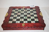 Closed folding chessboard showing carved wooden frame with dragon motifs, floral patterned board squares, and brass latch and corner protectors.