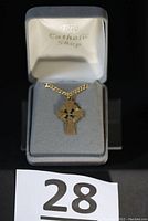 Pendant displayed in a grey jewelry box labeled 'The Catholic Shop'. Shows the full pendant and chain from a distance.