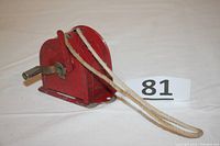 Side angle view of the red metal retractable clothesline dispenser showing the hand crank and the double clothesline extending from the unit.