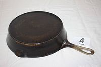 Side and handle profile of vintage cast iron skillet Wagner Ware Sidney with flat bottom, needing cleaning, showing overall shape and handle loop.