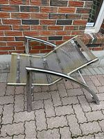 Side angled view of the lounge chair exposing the chrome frame and spaghetti strips seat and backrest.