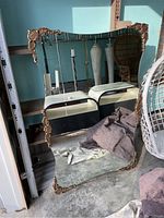 Full view of the vintage ornate brass mirror showing its size, frame, and wavy shape.