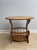 Front view of vintage wooden oval top side table with curved leg supports and built-in rack for vinyl records storage