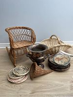 Photo showing all items in the lot including wicker rocking chair, wicker horn basket, wicker trivets, wicker basket champagne bucket and metal champagne bucket.