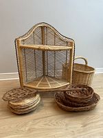 Small corner wicker shelf with several wicker baskets and trivets arranged at base