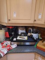 Photo showing countertop with Cuisinart grill, Bravetti cooking pot, Yogourmet yogurt maker, air fryer, kettle, food processor, and kitchen appliances clustered together.