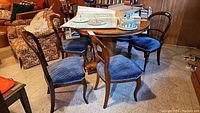 Six balloon back chairs around a wooden table, with blue upholstered seats and wooden curved legs.