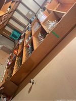 Full view of shelves with multiple rows of glass jars, plastic containers, and lids in basement storage room.