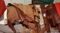 Several brown leather hides spread on a surface showing natural edges and texture.
