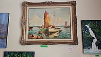 Framed oil painting hung on a wall showing several boats, with an ornate classical-style frame.