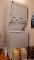 Front view of white stackable washer and dryer unit in room with control panel visible