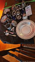 Overview of silver items including serving bowl, baskets, glass vessels, napkin rings, condiment dishes, and spoons