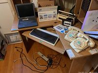Wide view showing all items on desk including laptop, radios, phones, keyboard, and printer box