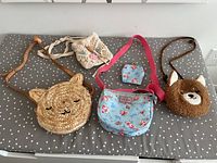 All four little girls purses with matching change purse laid out on polka dot surface, showing straps and designs